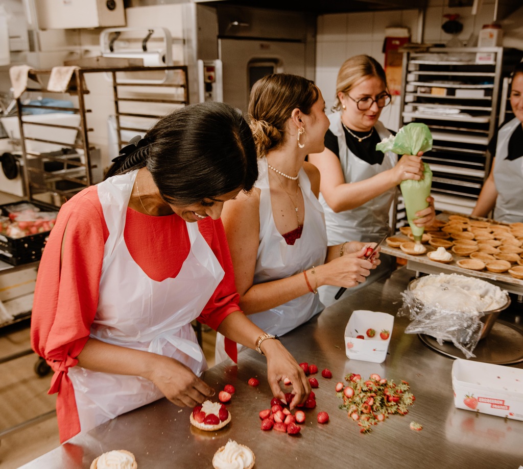 Teilnehmende an einem Schloss-Beck-Backworkshop dekorieren gemeinsam kleine Gebäckstücke.